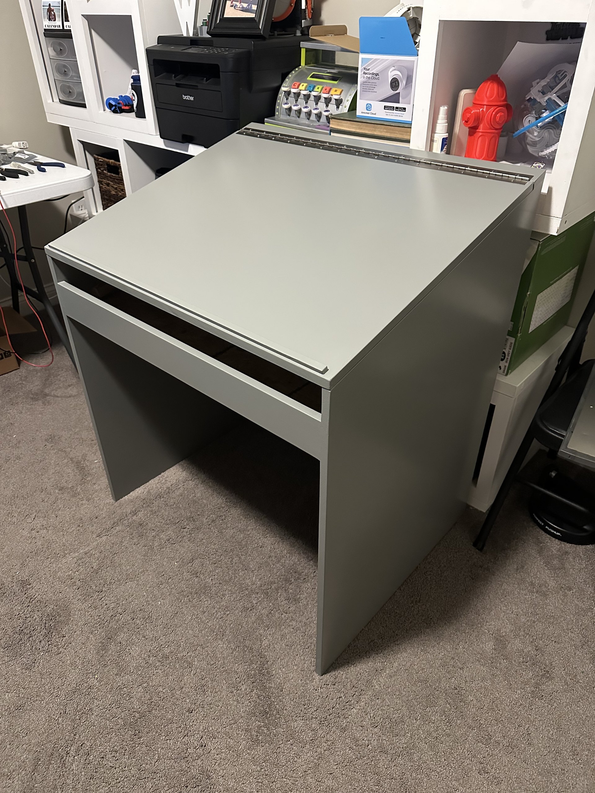Finished gray desk with the lid closed and a piano hinge along the back