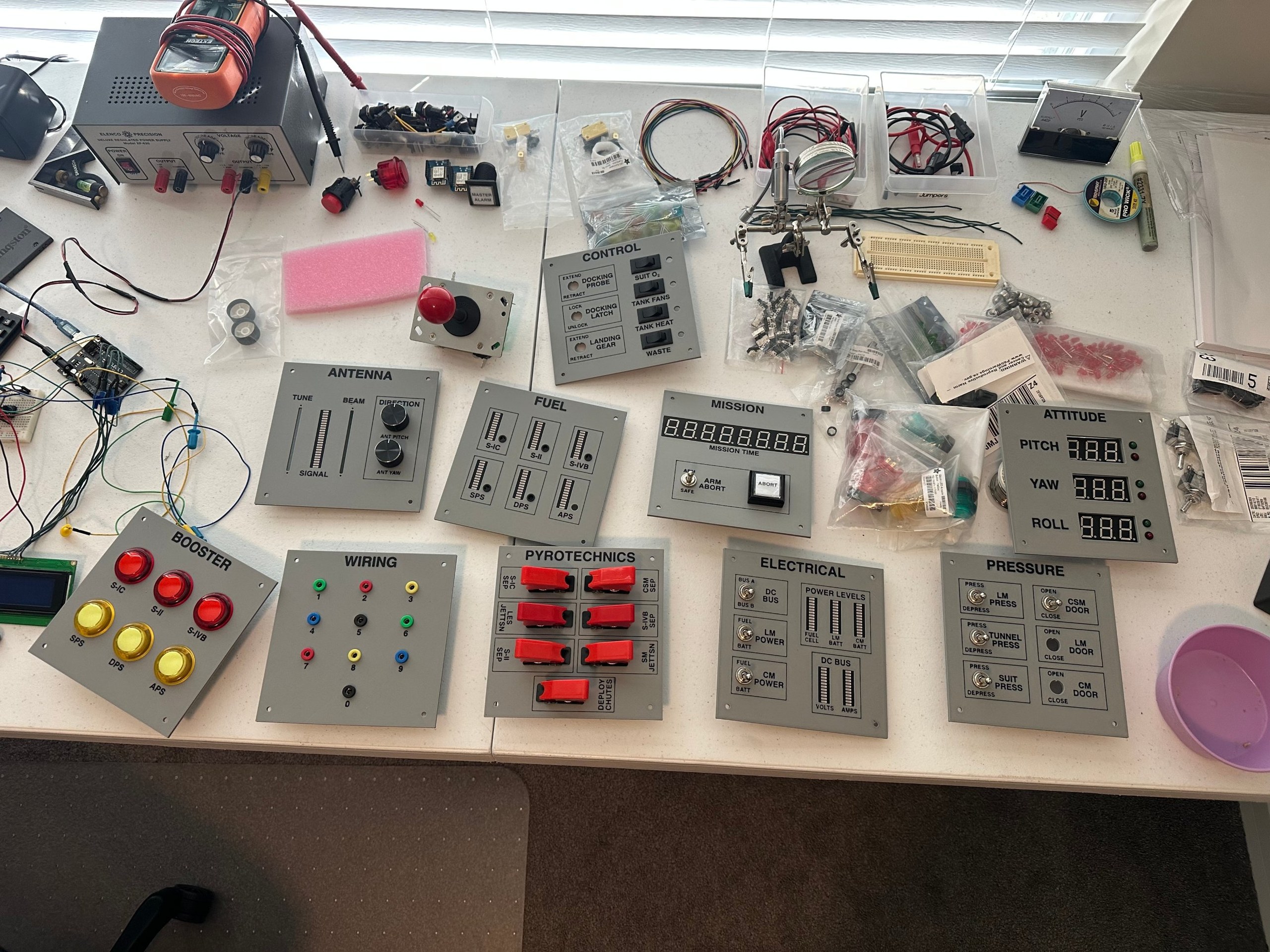 Printed Apollo simulator panels laid out on a workbench with components installed